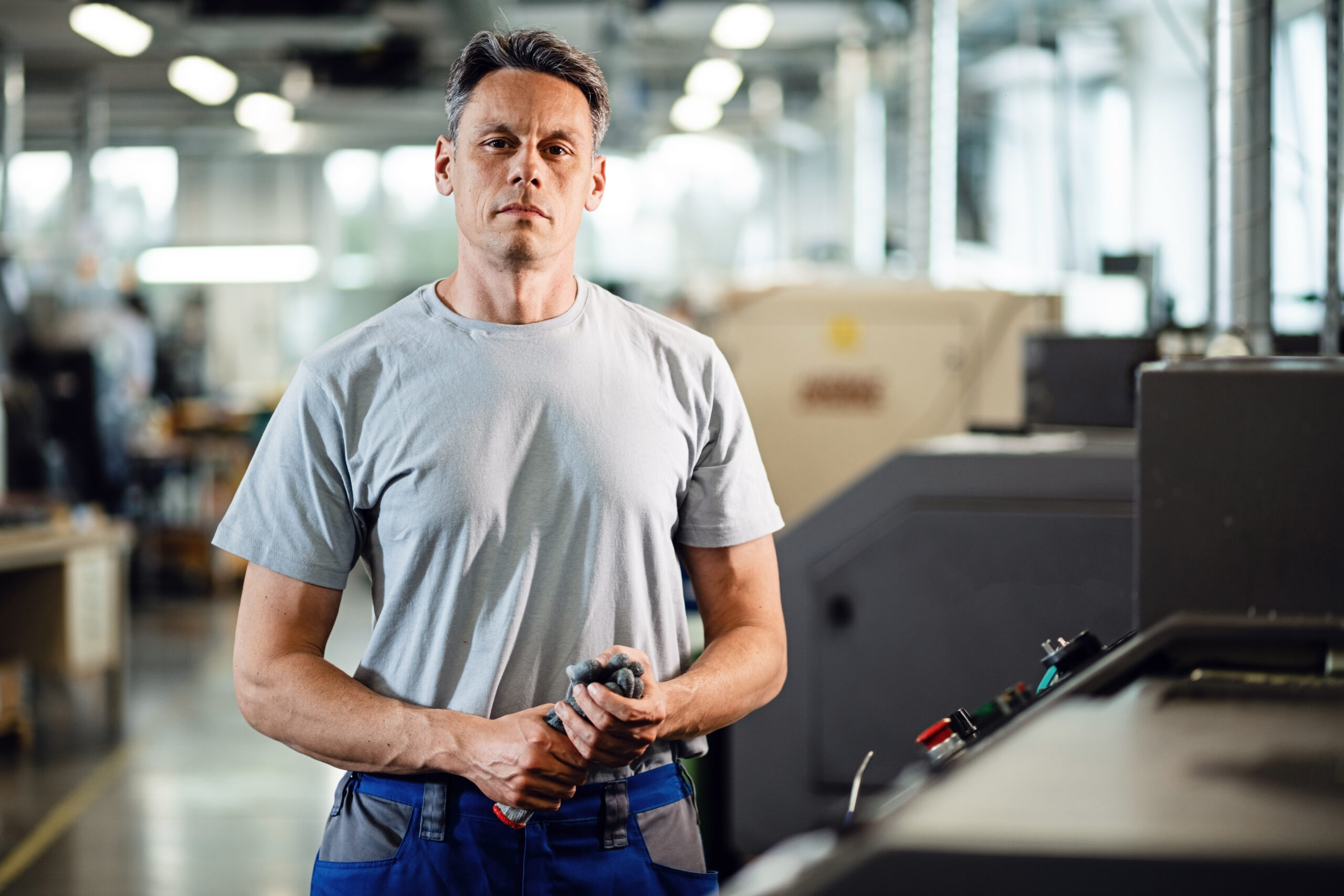 Portrait of CNC machine machine operator standing in a factory and looking at camera.