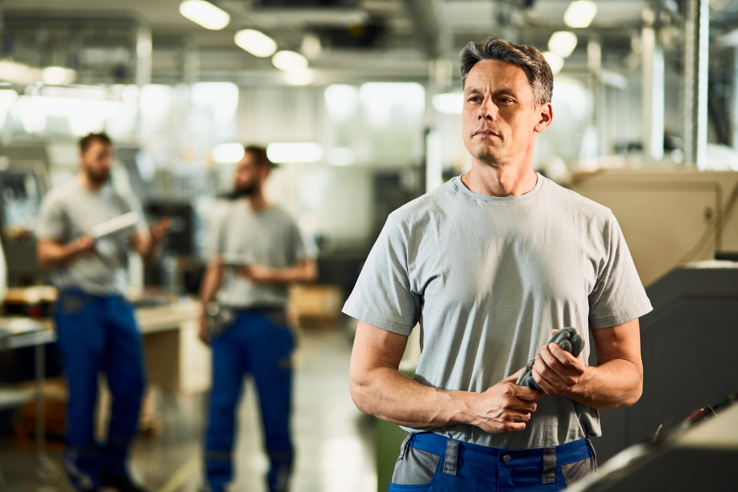 Portrait of mid adult CNC operator looking away while standing in a factory.